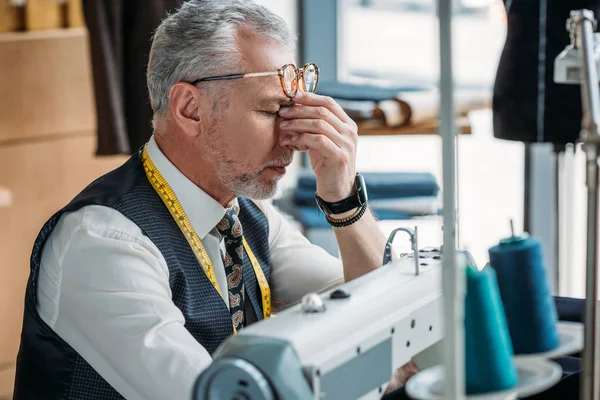 Beau tailleur fatigué touchant nez-pont à l'atelier de couture — Photo de stock