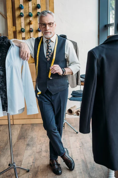 Handsome tailor leaning on mannequin at sewing workshop — Stock Photo