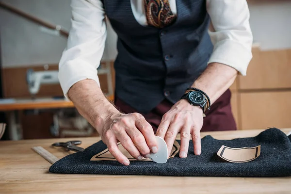 Cropped shot of stylish tailor marking cloth pattern with chalk at sewing workshop — Stock Photo