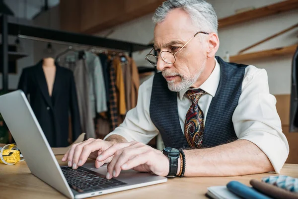 Nahaufnahme Porträt einer hübschen Schneiderin, die in der Nähwerkstatt mit Laptop arbeitet — Stockfoto