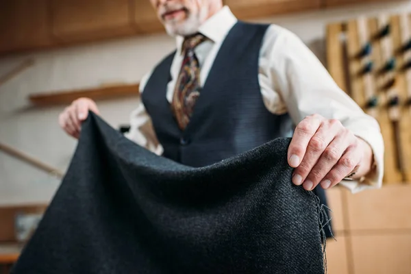 Plan recadré de tailleur mature avec tissu gris à l'atelier de couture — Photo de stock