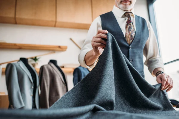 Plan recadré de tailleur mature élégant avec tissu gris à l'atelier de couture — Photo de stock