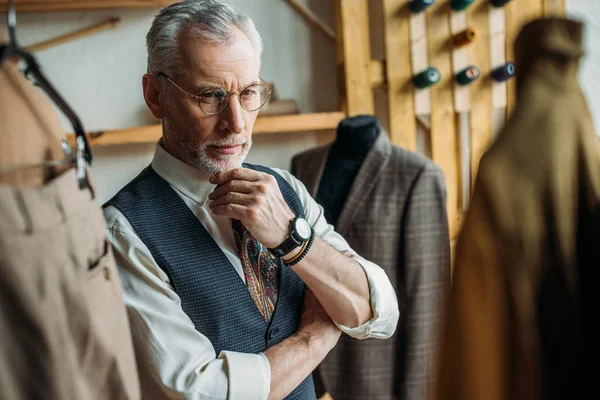 Schöner älterer Mann schaut sich Jacken auf Kleiderbügeln im Geschäft an — Stockfoto