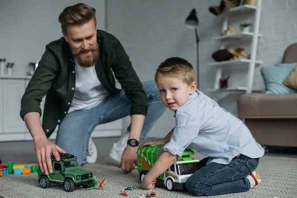 Pai e filho brincando com carros de brinquedo juntos no chão em casa — Fotografia de Stock