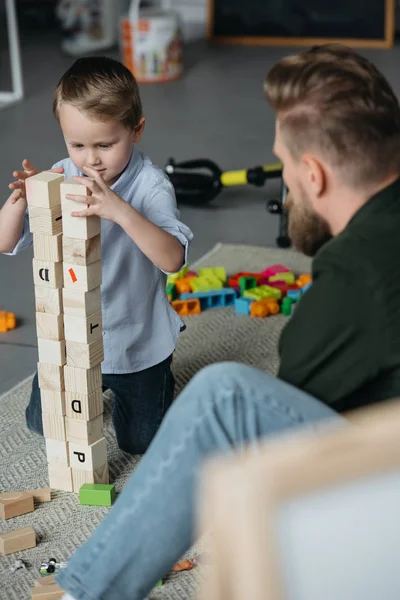 Foco seletivo de pai e filho brincando com blocos de madeira juntos em casa — Fotografia de Stock
