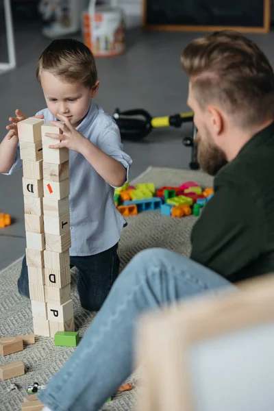 Selective focus of father and son playing with wooden blocks together at home — Stock Photo