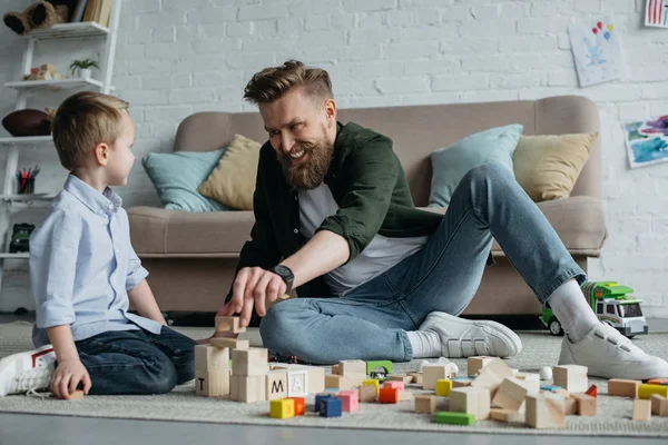Щасливий батько і син грають з дерев'яними блоками вдома — стокове фото