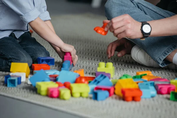 Vue partielle de la famille jouant avec des blocs colorés ensemble à la maison — Photo de stock