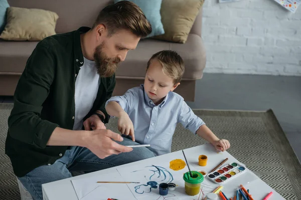 Vater und kleiner Sohn nutzen Smartphone gemeinsam zu Hause — Stockfoto