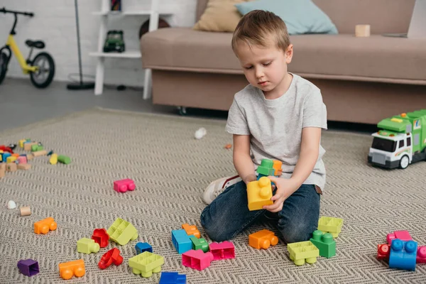 Little boy playing with colorful blocks on floor at home — Stock Photo