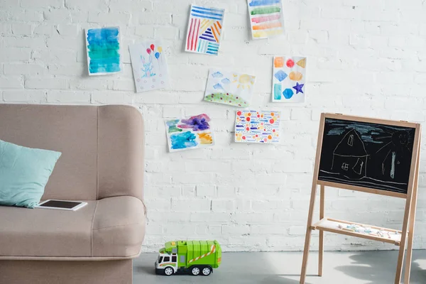 Vista de perto do quarto infantil vazio com sofá, quadro-negro e caminhão de brinquedo no chão — Fotografia de Stock