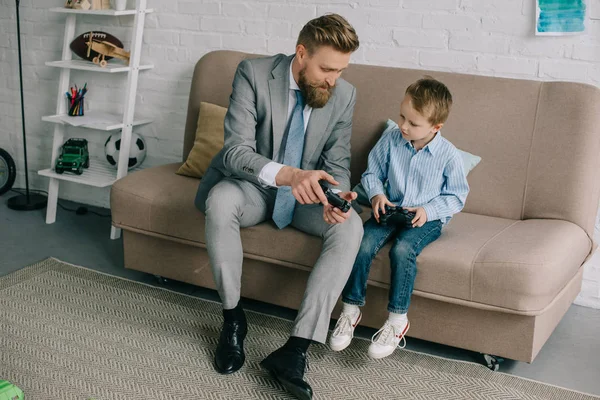 Businessman and little son playing video games together at home, work and life balance concept — Stock Photo