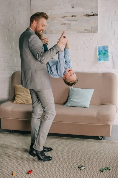 Hombre de negocios en traje que se divierten junto con su hijo pequeño en el hogar, el trabajo y el concepto de equilibrio de vida - foto de stock