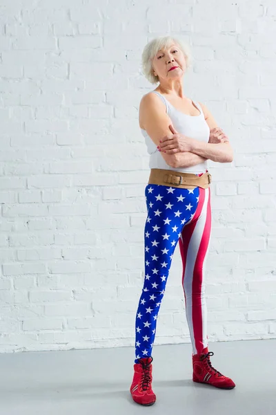 Femme âgée confiante en vêtements de sport debout avec les bras croisés et regardant la caméra — Photo de stock