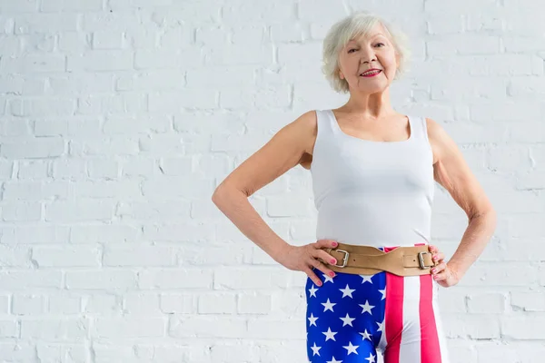 Glückliche Seniorin in Sportkleidung, die Hände auf der Taille und lächelnd in die Kamera — Stockfoto