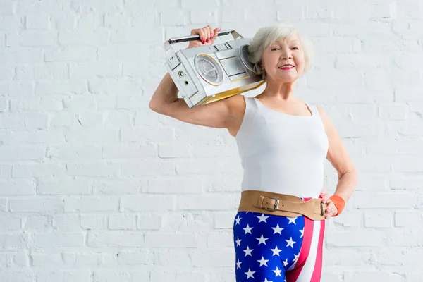 Happy senior sportswoman holding tape recorder and smiling at camera — Stock Photo