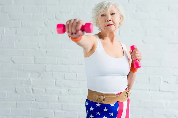 Femme âgée active faisant de l'exercice avec haltères et détournant les yeux — Photo de stock