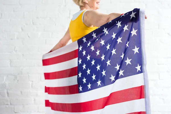 Tiro recortado de desportista sênior segurando bandeira americana — Fotografia de Stock