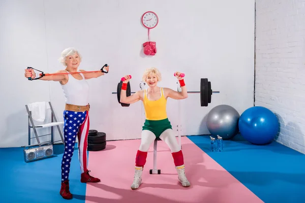 Femmes âgées sportives faisant de l'exercice et souriant à la caméra dans la salle de gym — Photo de stock