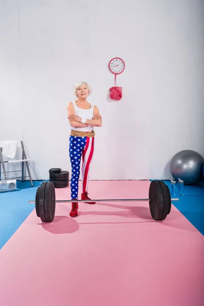 Confident senior sportswoman standing with crossed arms and smiling at camera — Stock Photo