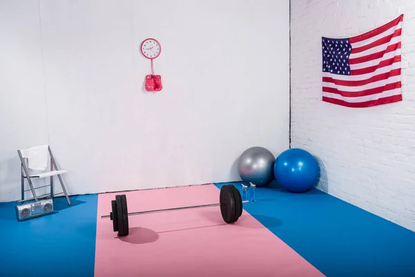 Bandera americana, barbell, guantes de boxeo, pelotas de ajuste y grabadora en el gimnasio - foto de stock