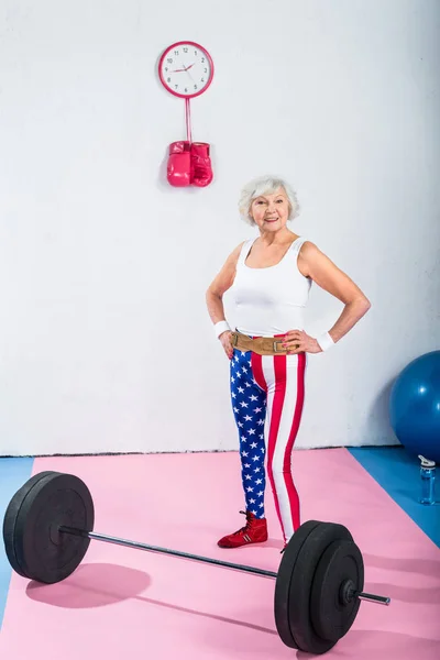 Patriotique sportif senior debout avec les mains sur la taille et souriant à la caméra — Photo de stock