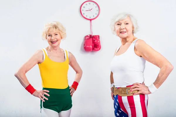 Heureux sportifs seniors debout avec les mains sur la taille et souriant à la caméra — Photo de stock