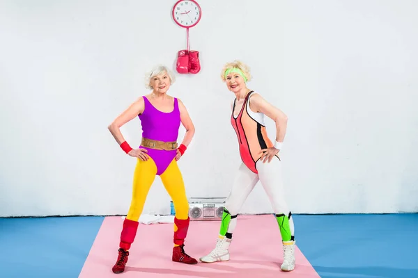 Full length view of sportive senior women training and smiling at camera — Stock Photo