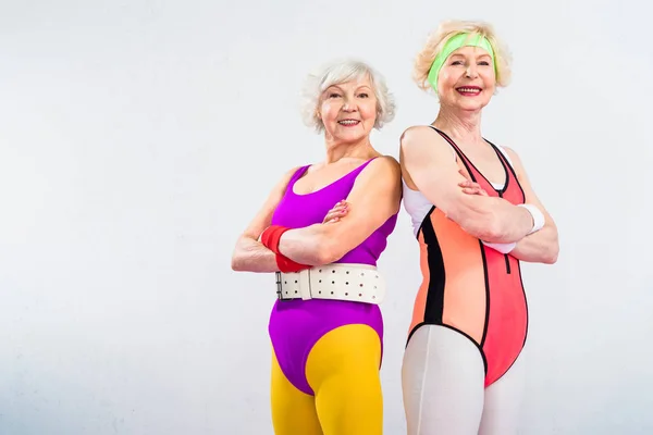 Felici sportivi anziani in piedi con le braccia incrociate e sorridente alla fotocamera isolata sul grigio — Foto stock