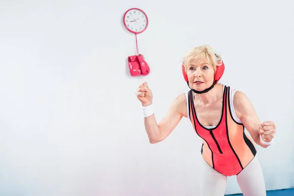 Focused senior sportswoman exercising and looking away on grey — Stock Photo