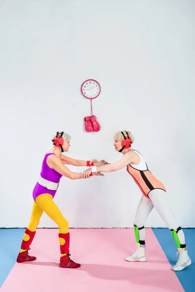 Ganzkörperansicht älterer Wrestlerinnen im Kopfschutz, die gemeinsam kämpfen — Stockfoto