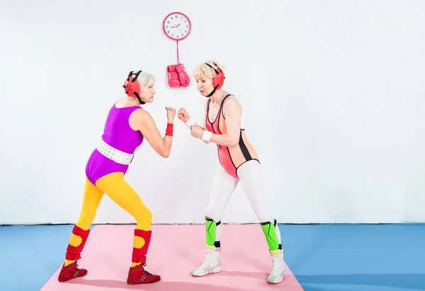 Visão lateral de lutadores sênior do sexo feminino na proteção da cabeça lutando juntos — Fotografia de Stock