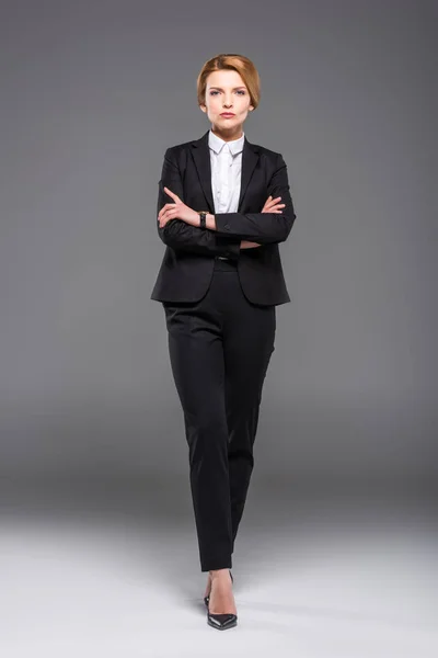 Confident businesswoman posing in formal wear with crossed arms, isolated on grey — Stock Photo