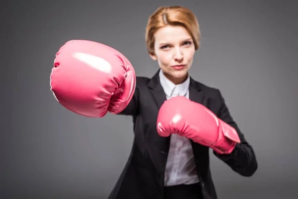 Enfoque selectivo de la mujer de negocios en traje y guantes de boxeo rosa, aislado en gris - foto de stock