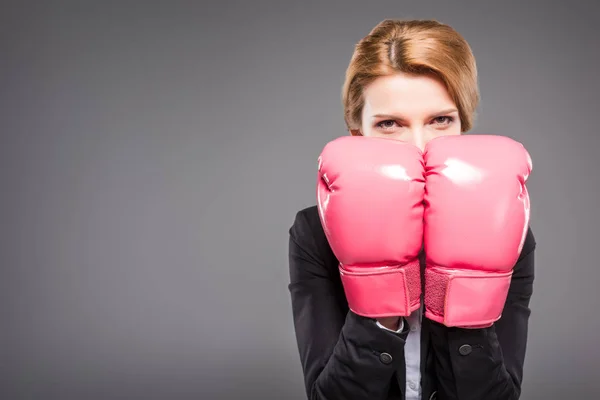 Blonde businesswoman in suit and pink boxing gloves, isolated on grey — Stock Photo