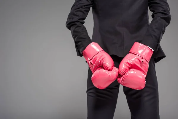 Partial view of businesswoman in pink boxing gloves, isolated on grey — Stock Photo