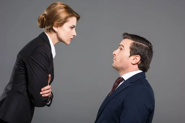 Angry female boss looking at scared businessman, isolated on grey, feminism concept — Stock Photo