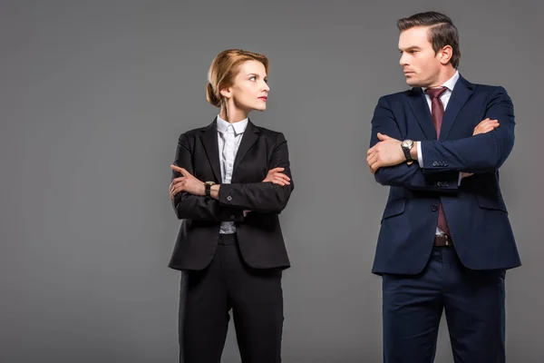 Empresária e empresária em traje formal posando com os braços cruzados, isolado em cinza — Fotografia de Stock