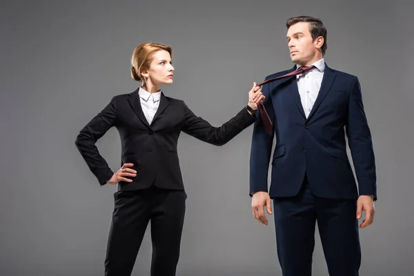 Aggressiva donna d'affari con in mano cravatta di uomo d'affari, isolato su grigio — Foto stock