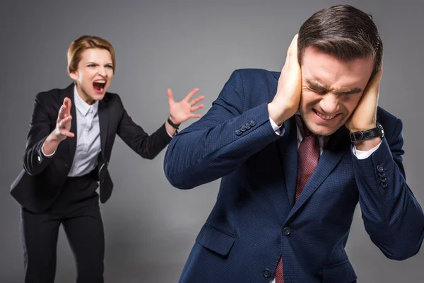 Aggressive female boss yelling at frightened businessman, isolated on grey — Stock Photo