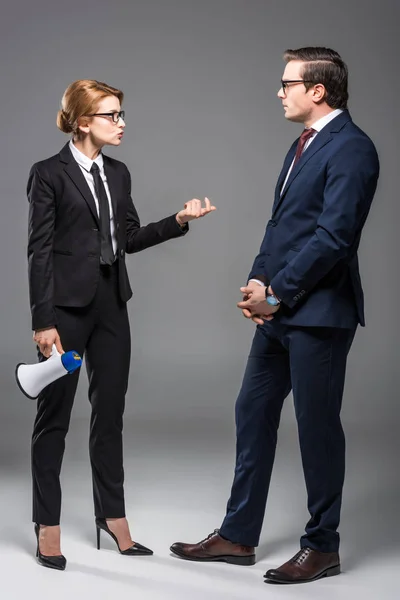 Angry businesswoman with megaphone talking to businessman, isolated on grey — Stock Photo