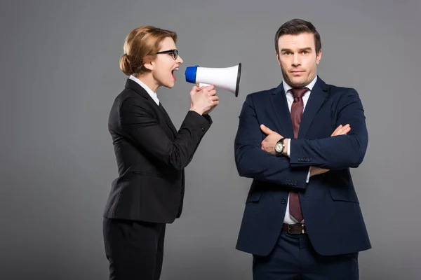 Donna d'affari aggressiva con corno di bue che urla all'uomo d'affari, isolata sul grigio, concetto di femminismo — Foto stock