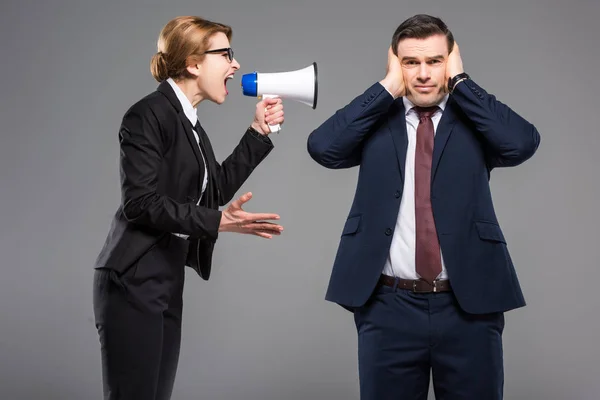 Angry businesswoman with bullhorn screaming at businessman, isolated on grey, feminism concept — Stock Photo