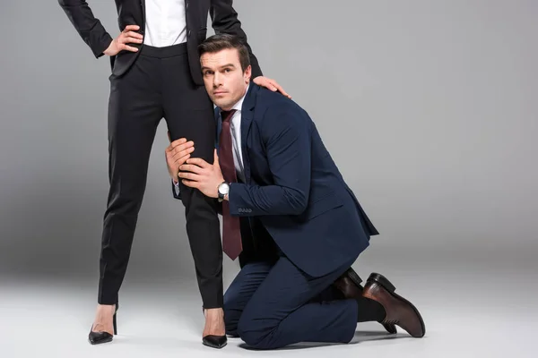 Feminist businesswoman dominating over businessman, isolated on grey — Stock Photo