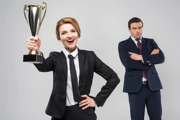 Excité femme d'affaires avec prix et contrarié homme d'affaires derrière, isolé sur gris — Photo de stock