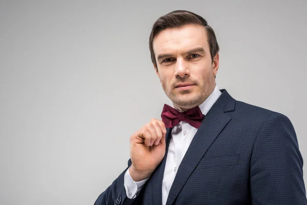 Portrait of handsome man posing in festive bow tie, isolated on grey — Stock Photo