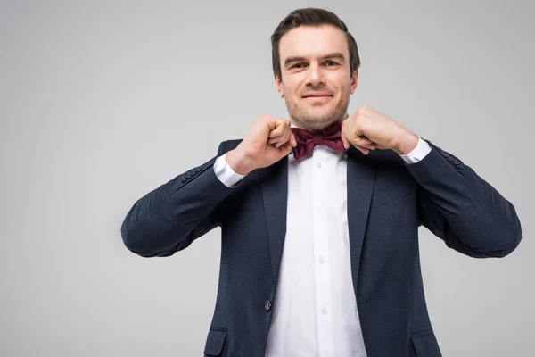 Handsome man posing in suit and bow tie, isolated on grey — Stock Photo