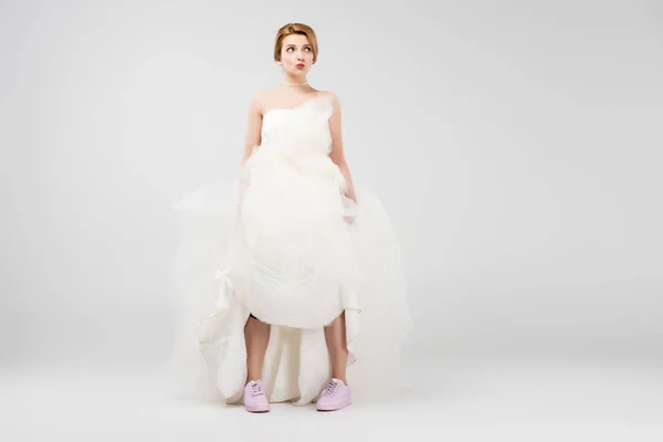 Sposa felice in abito da sposa bianco e scarpe da ginnastica rosa, isolato sul grigio, concetto di femminismo — Foto stock