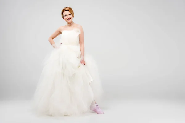 Mariée souriante en robe de mariée blanche et baskets roses, isolé sur gris, concept féminisme — Photo de stock