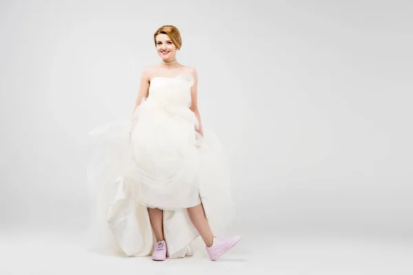 Novia en vestido de novia blanco y zapatillas de deporte de color rosa, aislado en gris, concepto de feminismo - foto de stock